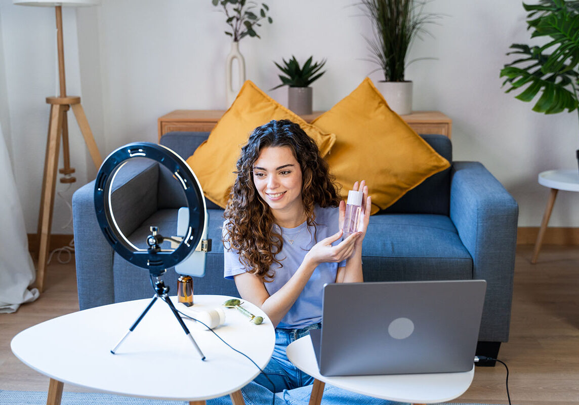 Curly-haired woman showcasing skincare products on camera